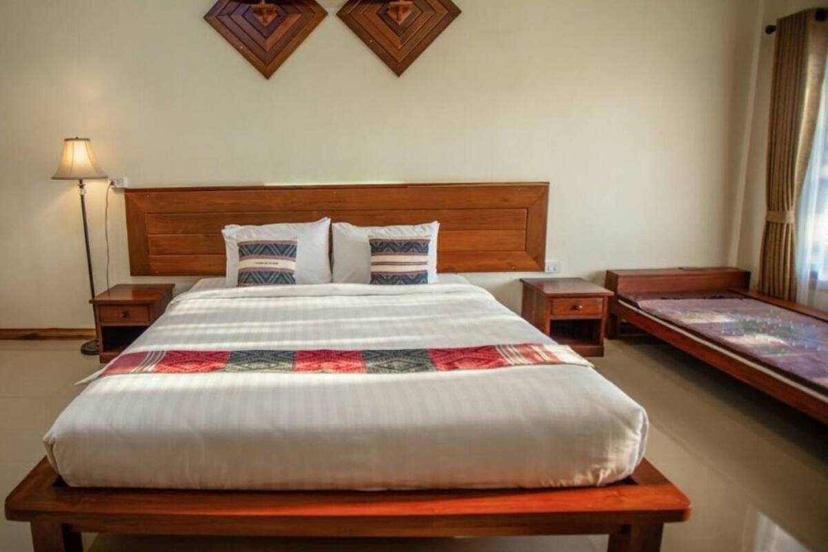 A neatly made bed with a wooden headboard, two bedside tables, a lamp, and a decorative wall piece.
