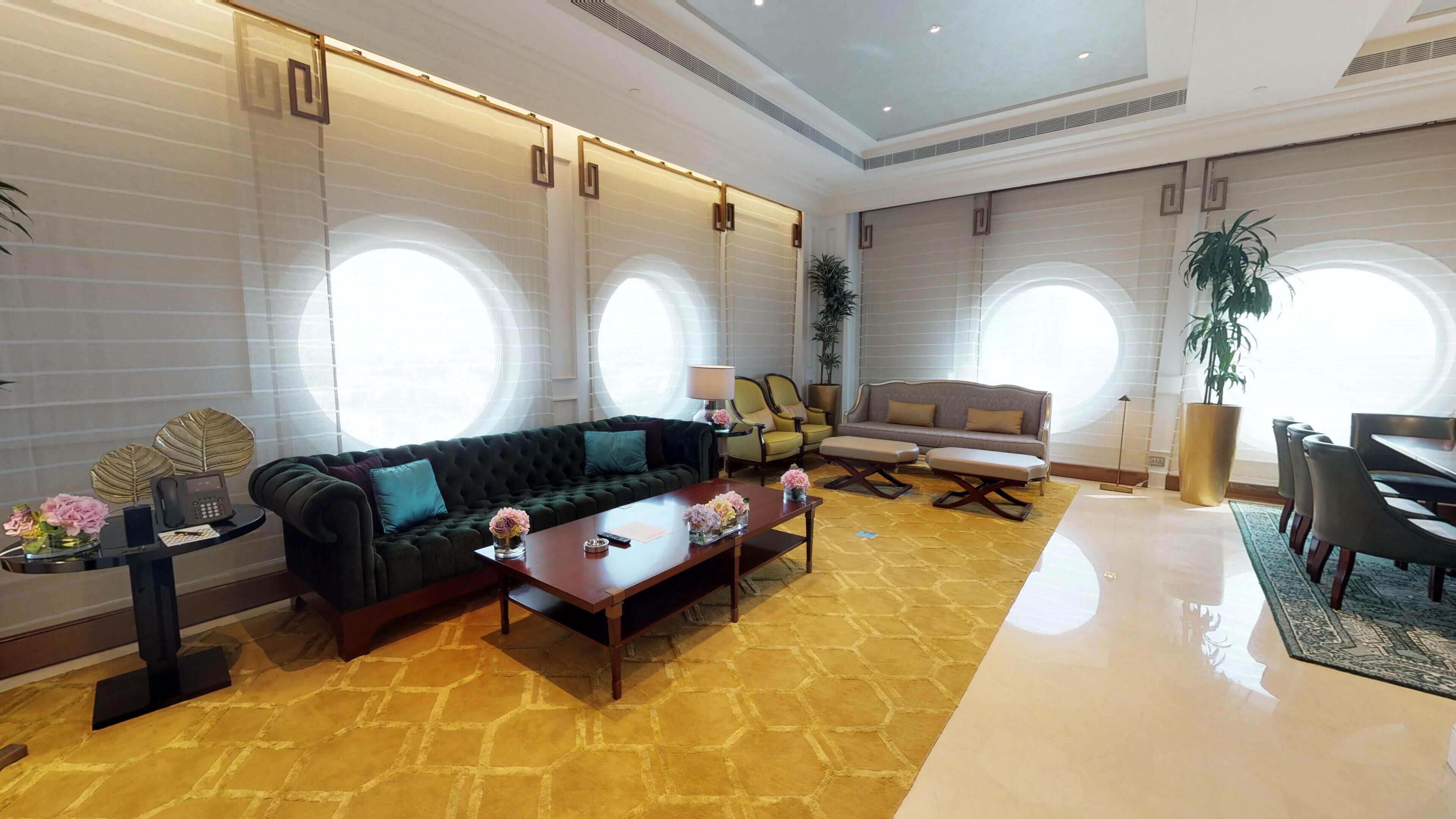 Una sala de estar moderna con un sofá, sillones, una mesa de centro y un comedor con sillas y una mesa.