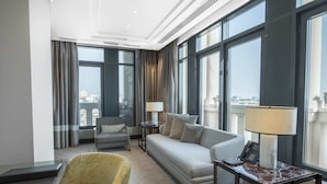 Una habitación de hotel moderna con sofá, sillón y una mesita con lámpara.
