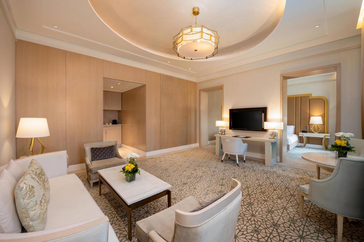 Een hotelkamer met een bank, fauteuil, televisie, bureau en een kamerbreed tapijt met dessin.