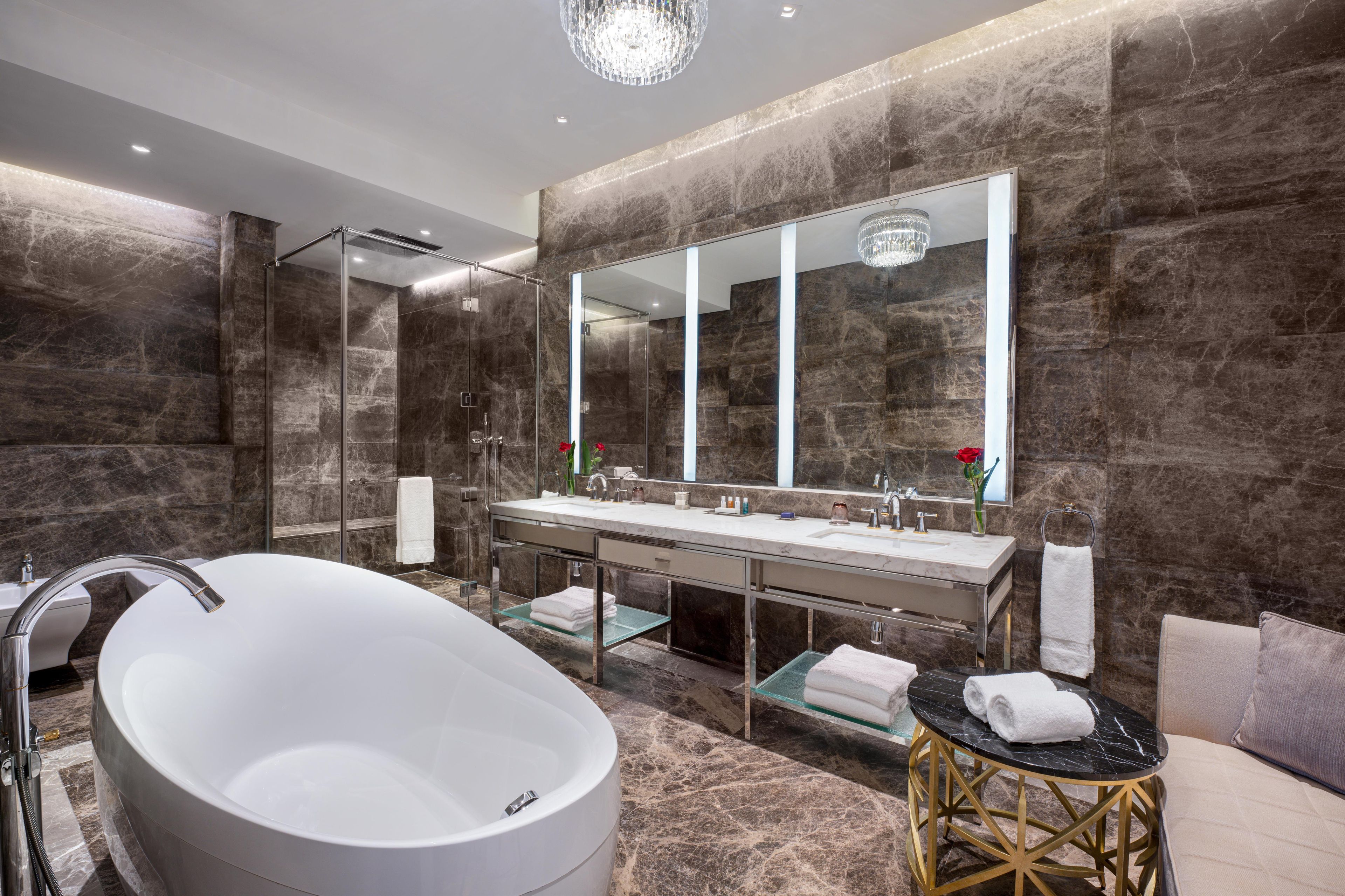 Un baño moderno con una bañera independiente, un espejo grande y una ducha con mampara de vidrio.
