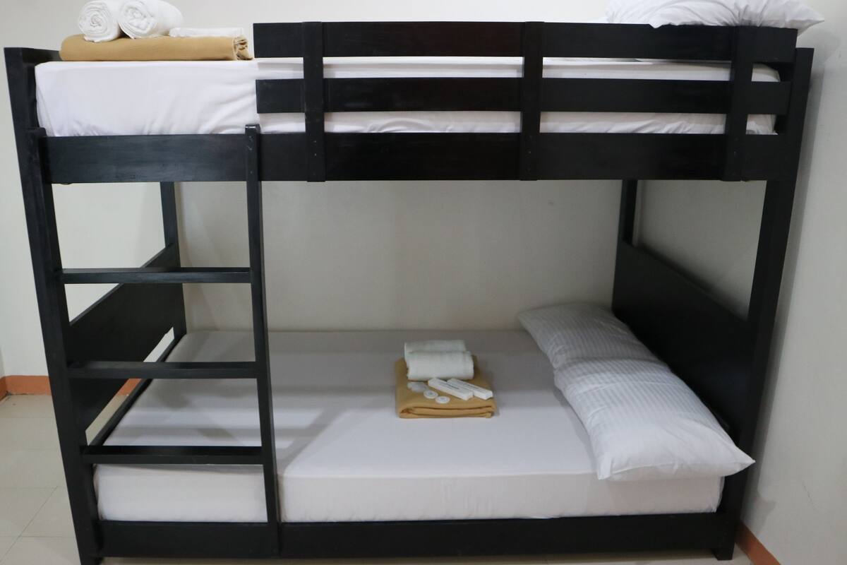 A bunk bed with a white mattress and a beige blanket.