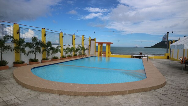 A swimming pool with a view of the sea, surrounded by yellow and white walls, and potted plants. - La Patricia de Baler (Baler)