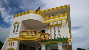 A multi-story building with a curved balcony and a green awning. - La Patricia de Baler (Baler)
