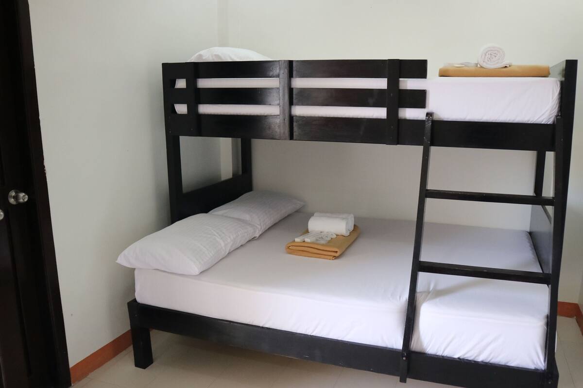 A bunk bed with white bedding and a towel on the top bunk.