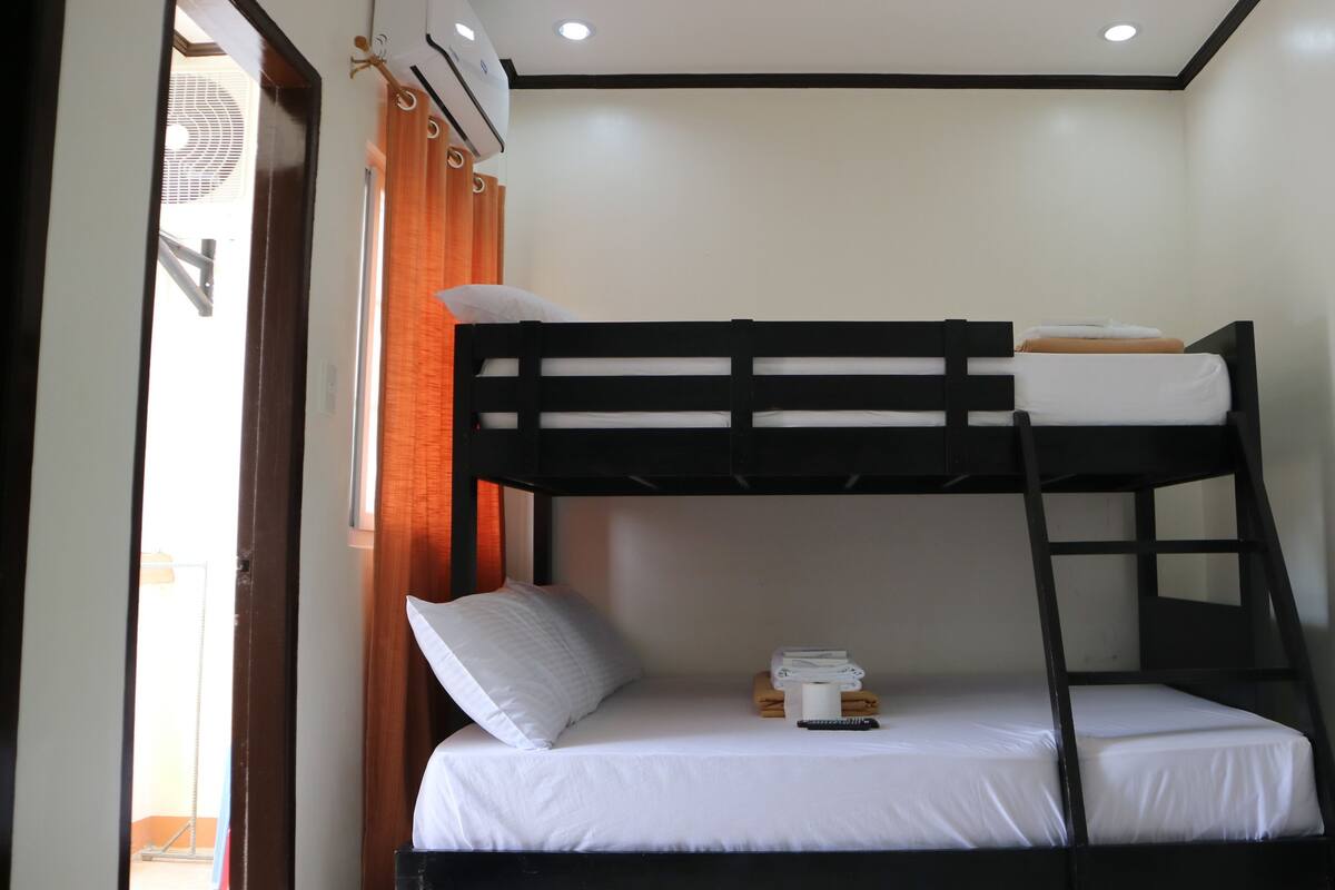 A bunk bed with white bedding and a remote control on the lower bunk.