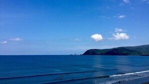 A beach with clear blue water and a distant mountain. - La Patricia de Baler (Baler)