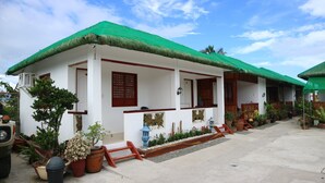 A white building with a green roof, wooden porch, and potted plants. - La Patricia de Baler (Baler)