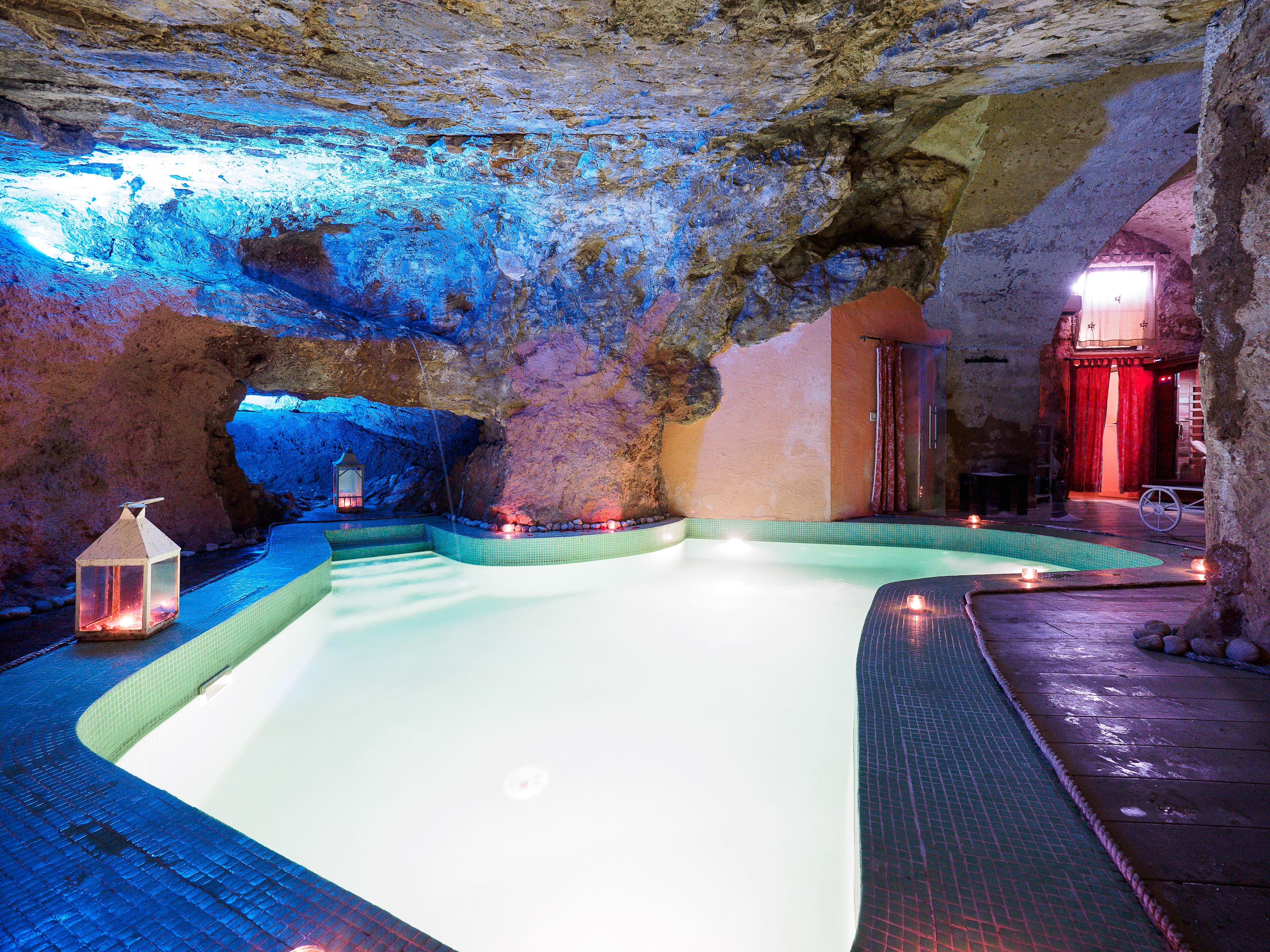 An indoor swimming pool with a tiled floor, a lantern, and a red curtain in the background.