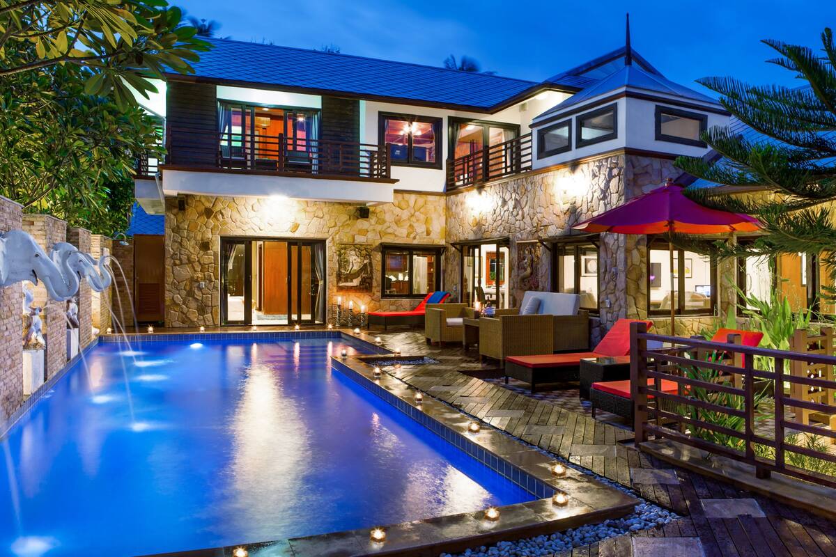 A two-story house with a swimming pool, outdoor seating, and a well-lit patio area.
