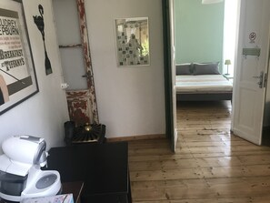 A room with a bed, a door leading to another room, a radiator, and a poster on the wall.