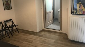 A room with a wooden floor, a door leading to a bathroom, and a radiator on the wall. - La Terrazza di Arturo (Turin)