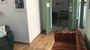 A room with a green door, a green sofa, a striped cushion, and a wooden floor. - La Terrazza di Arturo (Turin)