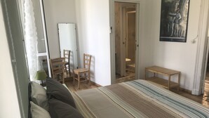 A bedroom with a bed, a chair, a small table, and a door leading to a bathroom. - La Terrazza di Arturo (Turin)