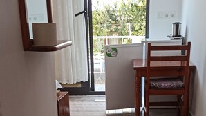 Un interior moderno con una mesa y sillas de madera para comer, una pequeña cocina y vistas a través de un ventanal.