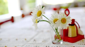 A clear glass vase with white flowers on a tablecloth.