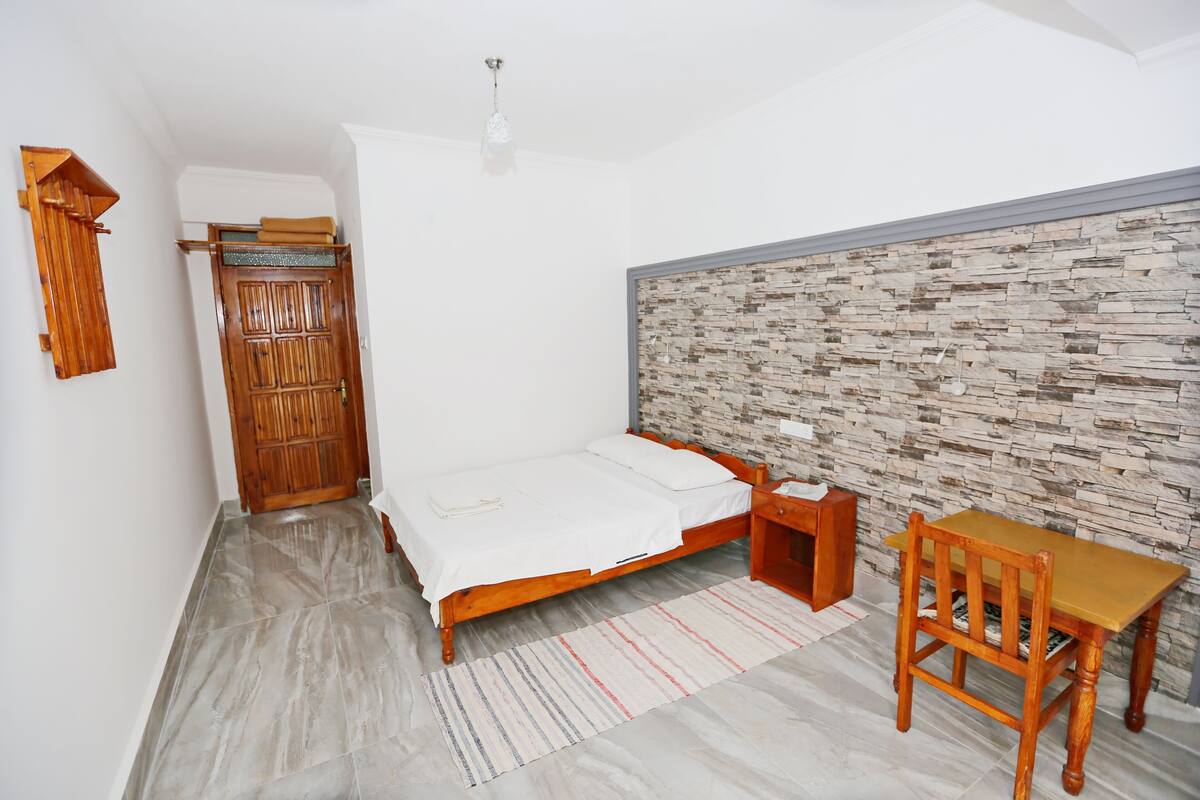 Un dormitorio con una cama, un armario de madera y una mesa con una silla.