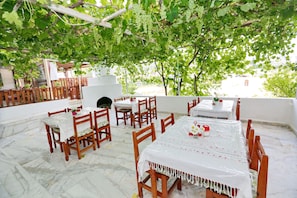 An outdoor dining area with tables and chairs, covered by a pergola with grapevines. - Sulo Pansiyon (Kas)