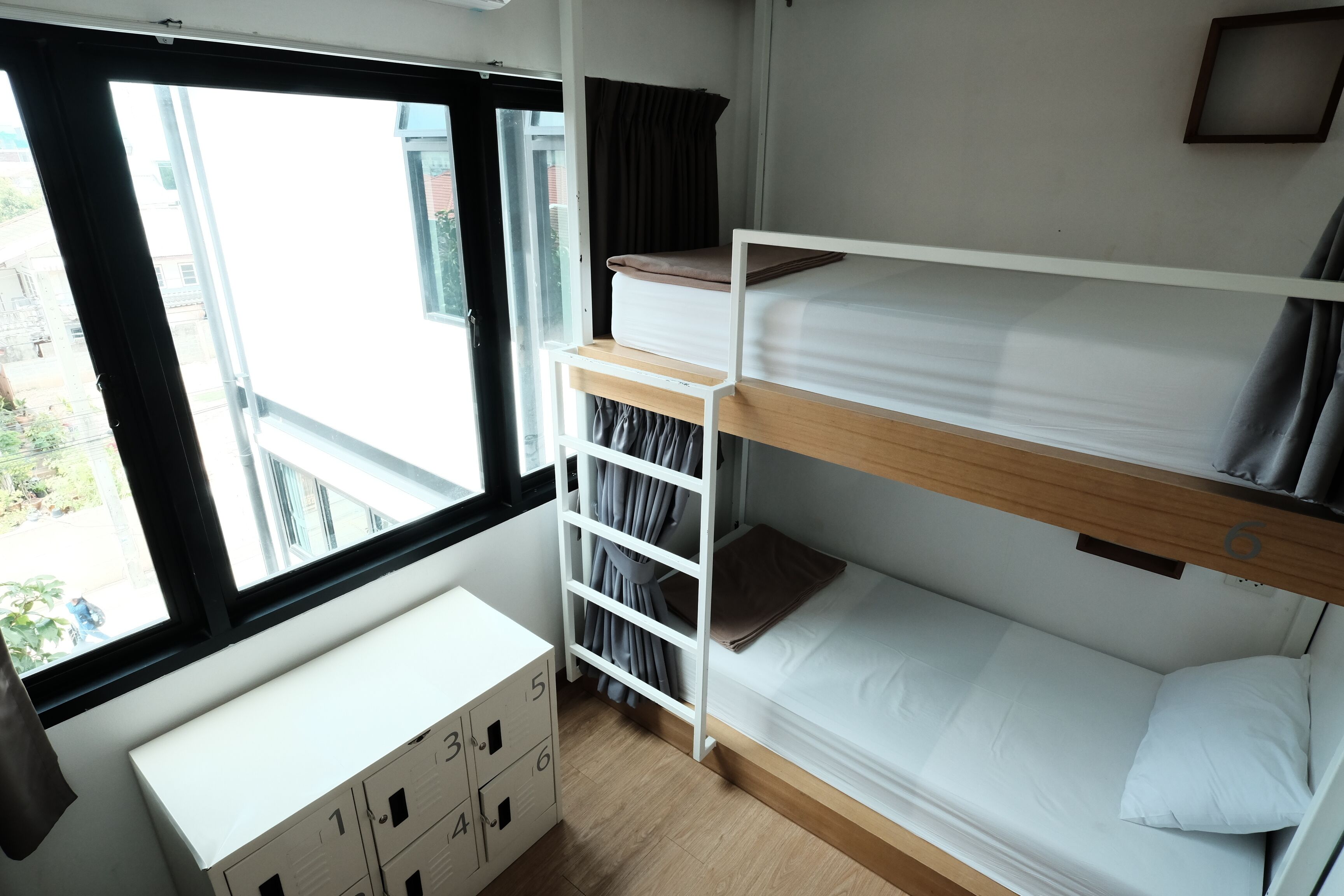 Une chambre avec un lit superposé, une fenêtre, un bureau et des placards de rangement.