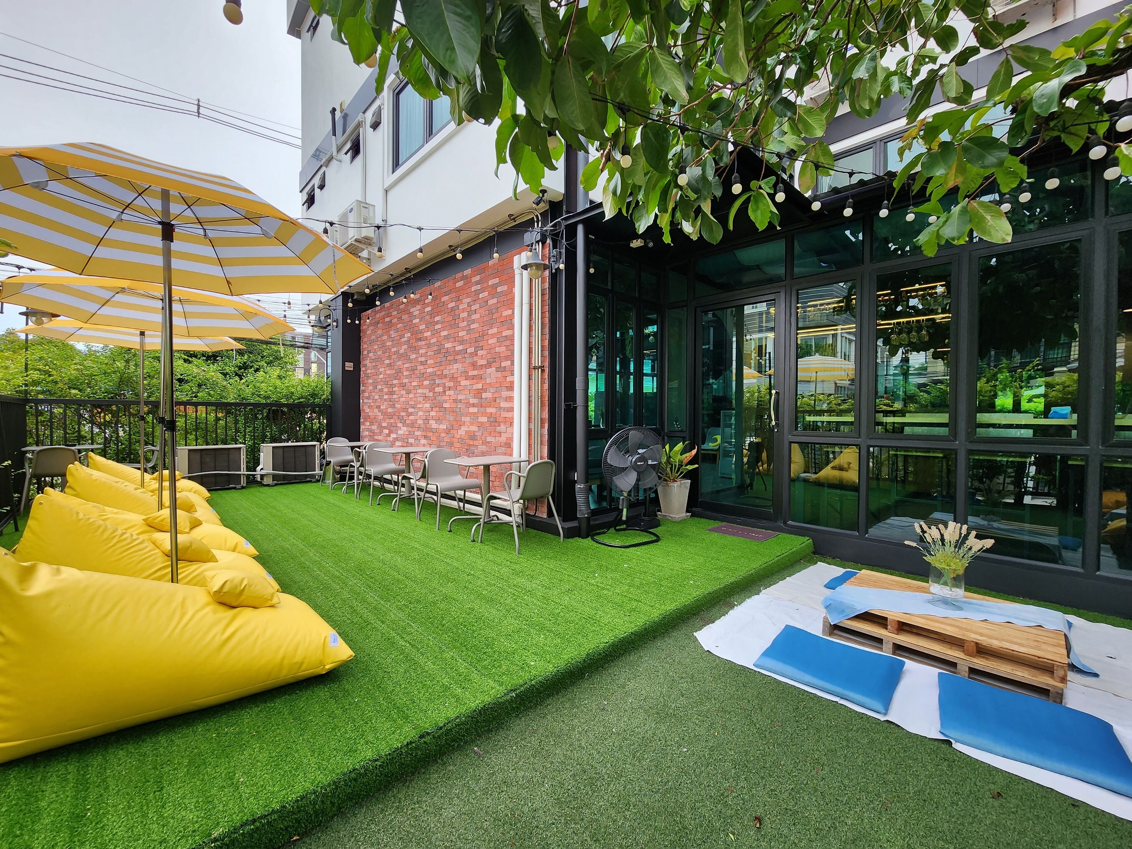 A patio area with artificial grass, yellow bean bag chairs, and outdoor tables.