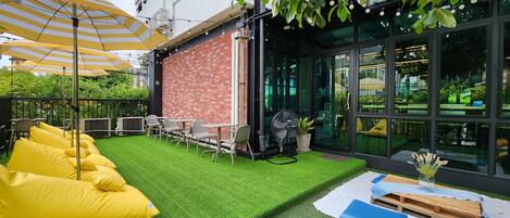 A patio area with artificial grass, yellow bean bag chairs, and outdoor tables.