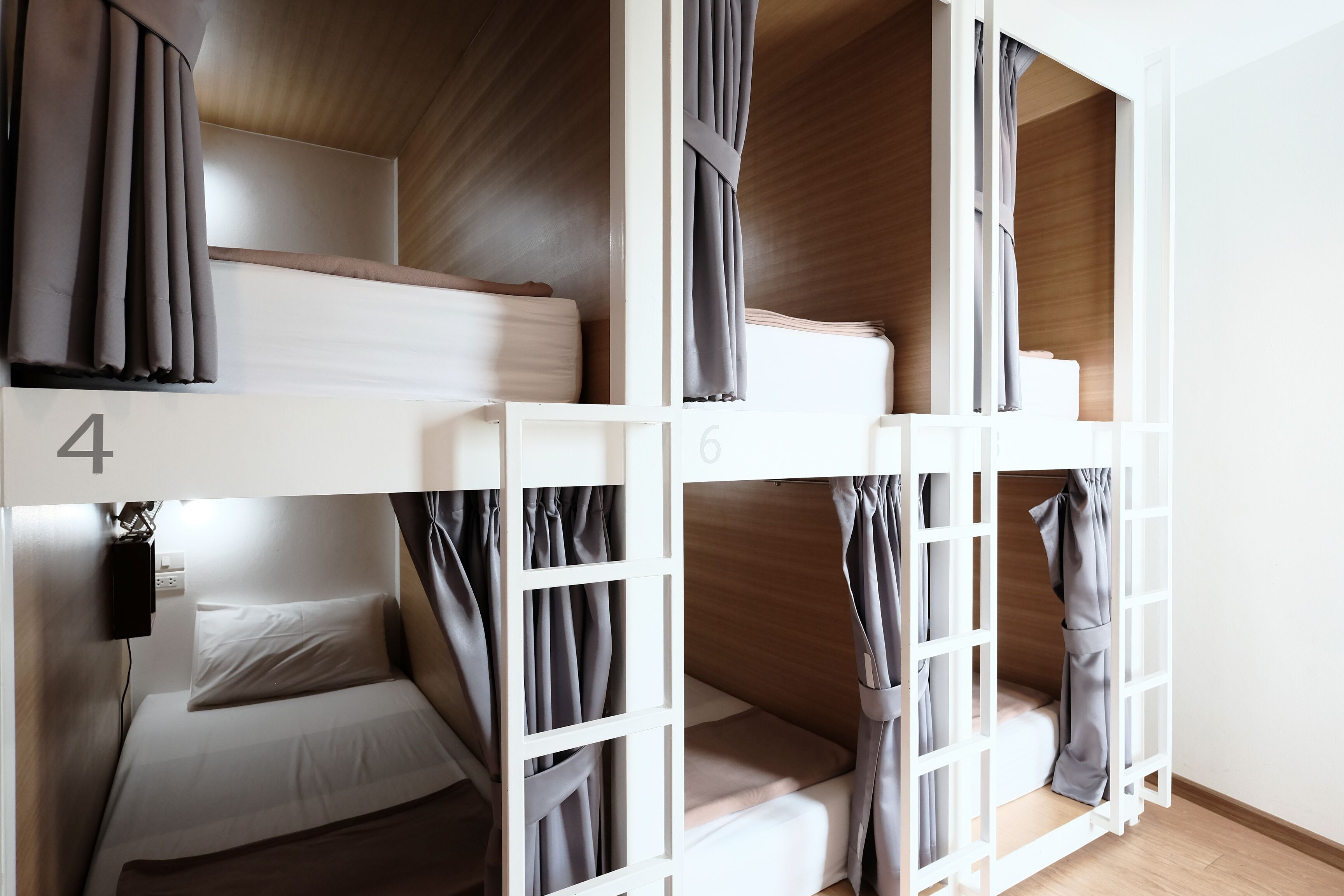A bunk bed room with numbers 4 and 6, wooden walls, and curtains.
