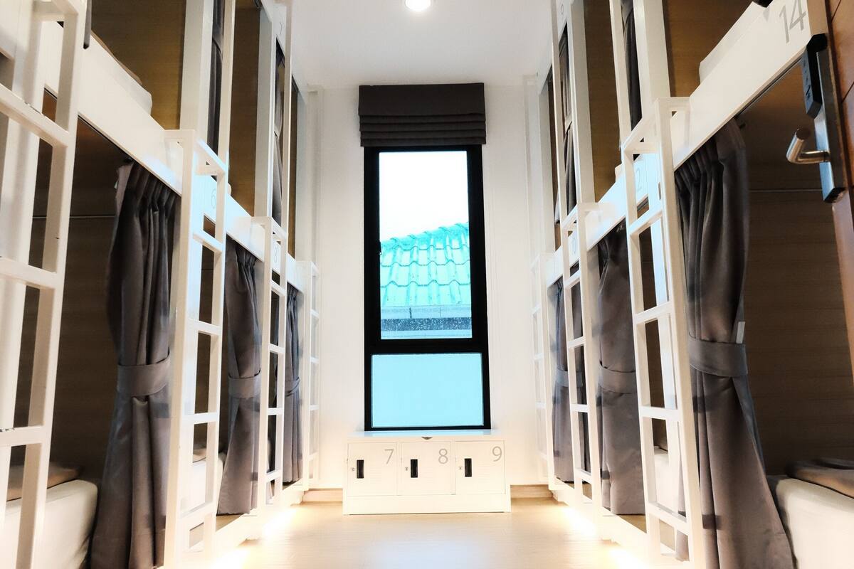 Ein Zimmer mit Etagenbetten, einem großen Fenster und einer Klimaanlage.