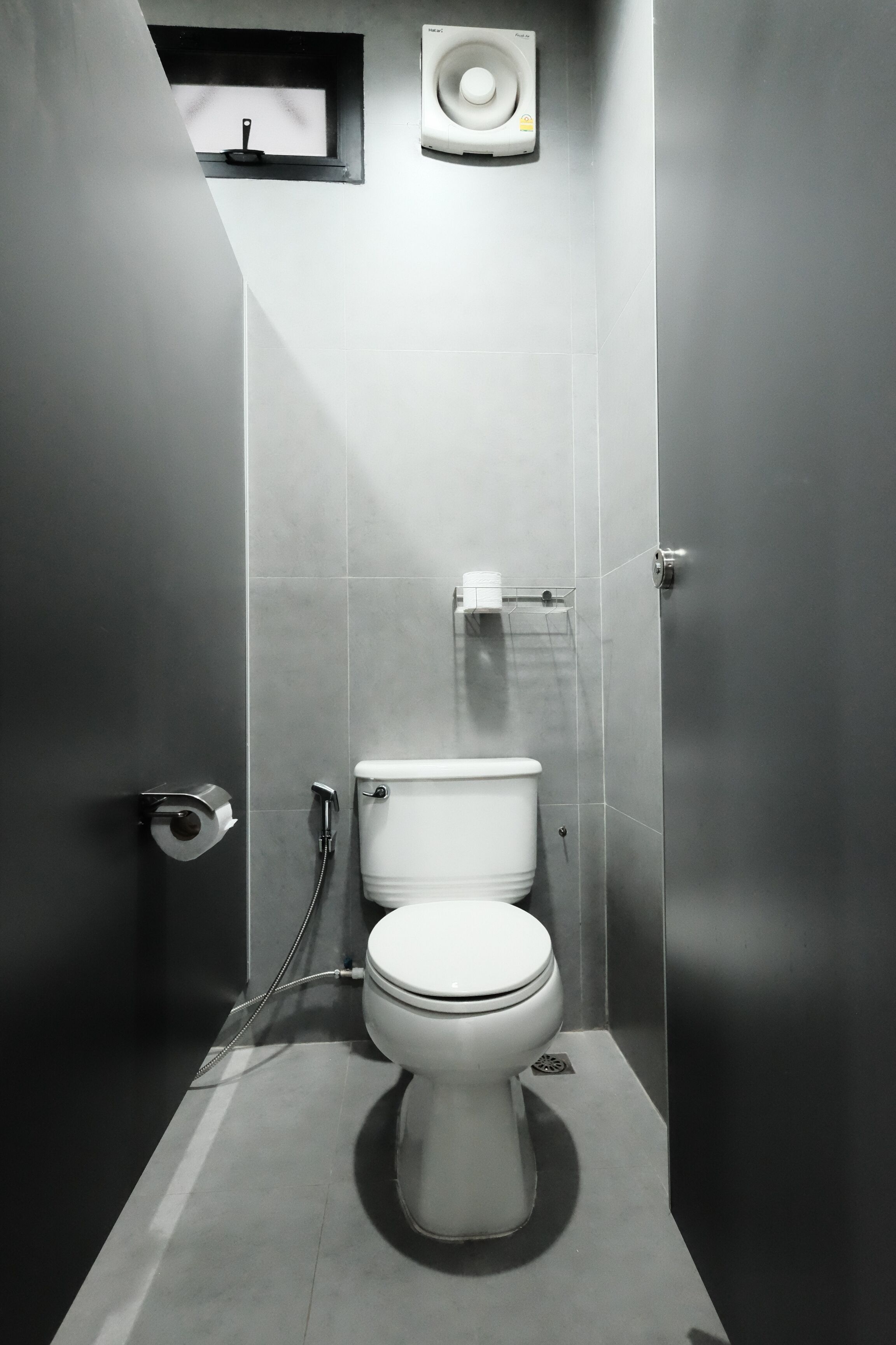 Ein modernes Badezimmer mit Toilette, Dusche und einem kleinen Fenster.