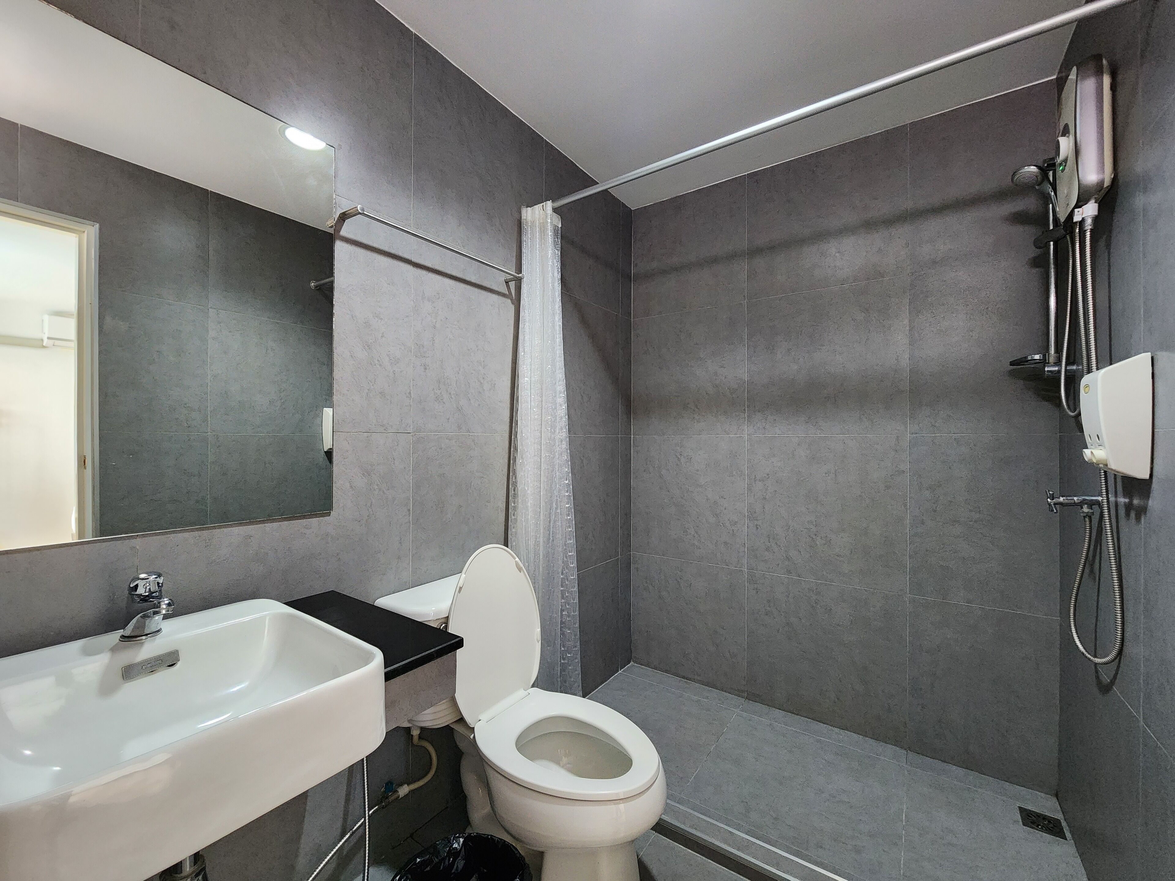 A modern bathroom with a white sink, toilet, and shower.