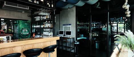 A bar area with stools, a counter, and shelves with bottles.