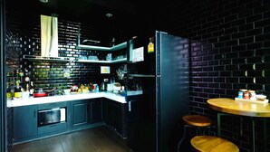 Une cuisine moderne avec des meubles de rangement noirs, un four encastré et une table à manger en bois, accompagnée de tabourets.
