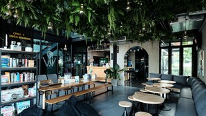 Un café moderne avec des plantes d’intérieur, des tables en bois et un espace salon.