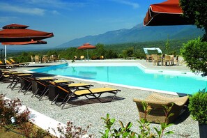 Una piscina al aire libre de temporada, sombrillas, tumbonas