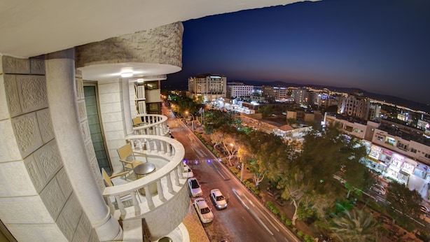 A nighttime view from a balcony overlooking a city street with buildings and cars. - Dweik Hotel 3 (Aqaba)