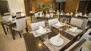 A hotel dining area with multiple tables set for guests, featuring modern decor and a central view of the hotel's interior. - Dweik Hotel 3 (Aqaba)