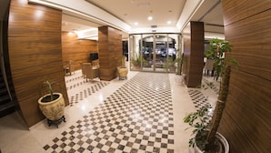 A hotel lobby with a checkered floor, wooden walls, and potted plants. - Dweik Hotel 3 (Aqaba)