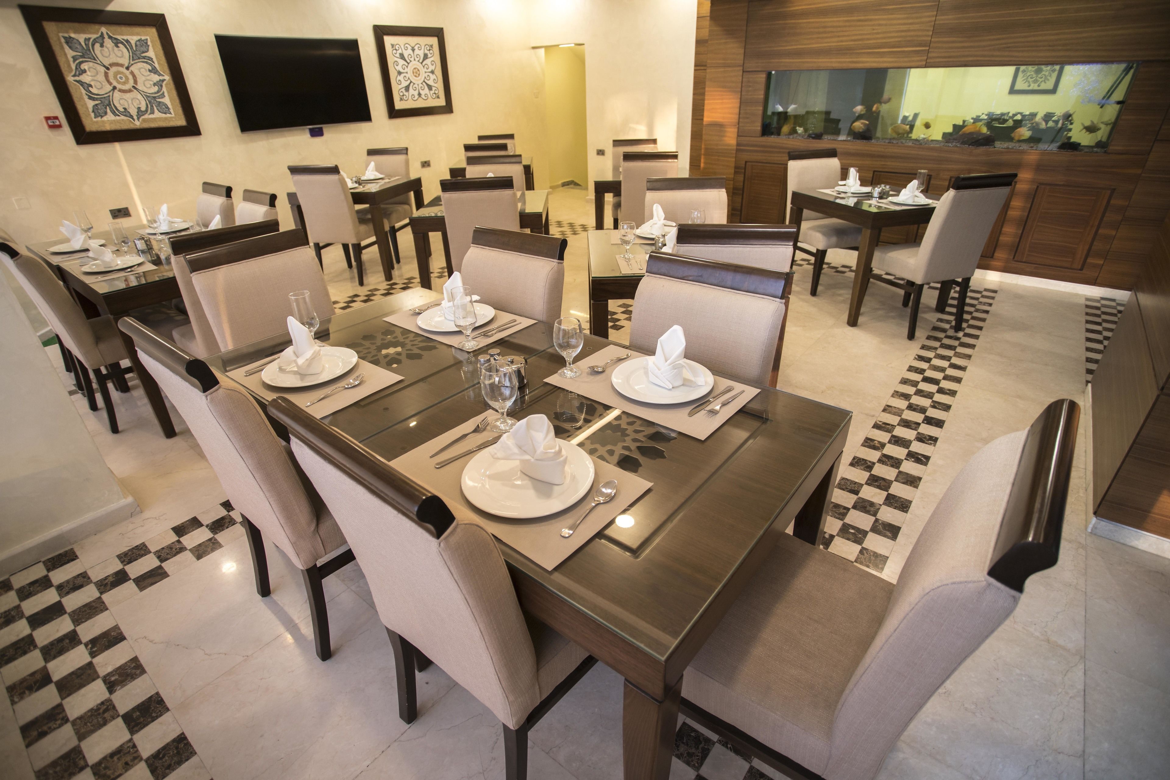 A dining area with multiple tables set for four, each with white plates, glasses, and cutlery.
