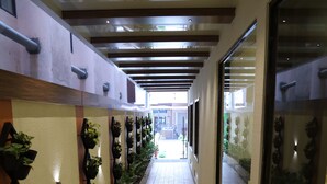 A corridor with a tiled floor, a wooden bench, and a wall-mounted planter with greenery. - Dr. Rajkumar International Hotel (Bengaluru)