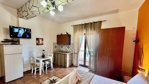 Une chambre d’hôtel compacte comprenant un coin cuisine, un lit, une télévision et une vue sur l’extérieur.
