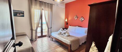 Quarto de hotel com cama, escrivaninha, cadeira, guarda-roupa e vista para o exterior.