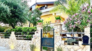 Un mur de pierre avec une porte, des plantes en pot et une enseigne indiquant « Casa Sorrento ».