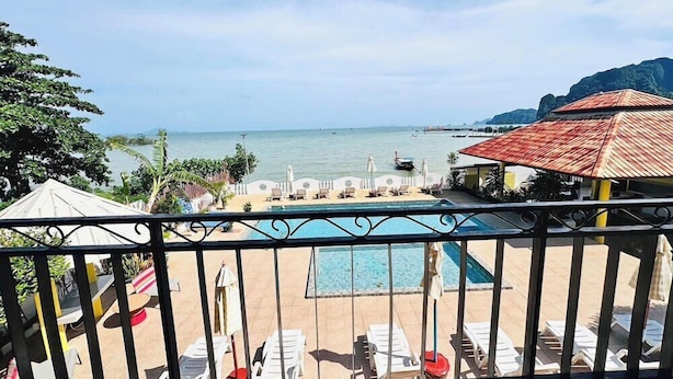 A pool area with lounge chairs and umbrellas, overlooking a calm sea and a mountainous landscape. - Anyavee Nam Mao Beach Resort (Krabi)