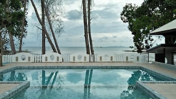 Una piscina al aire libre, sombrillas, sillones reclinables de piscina