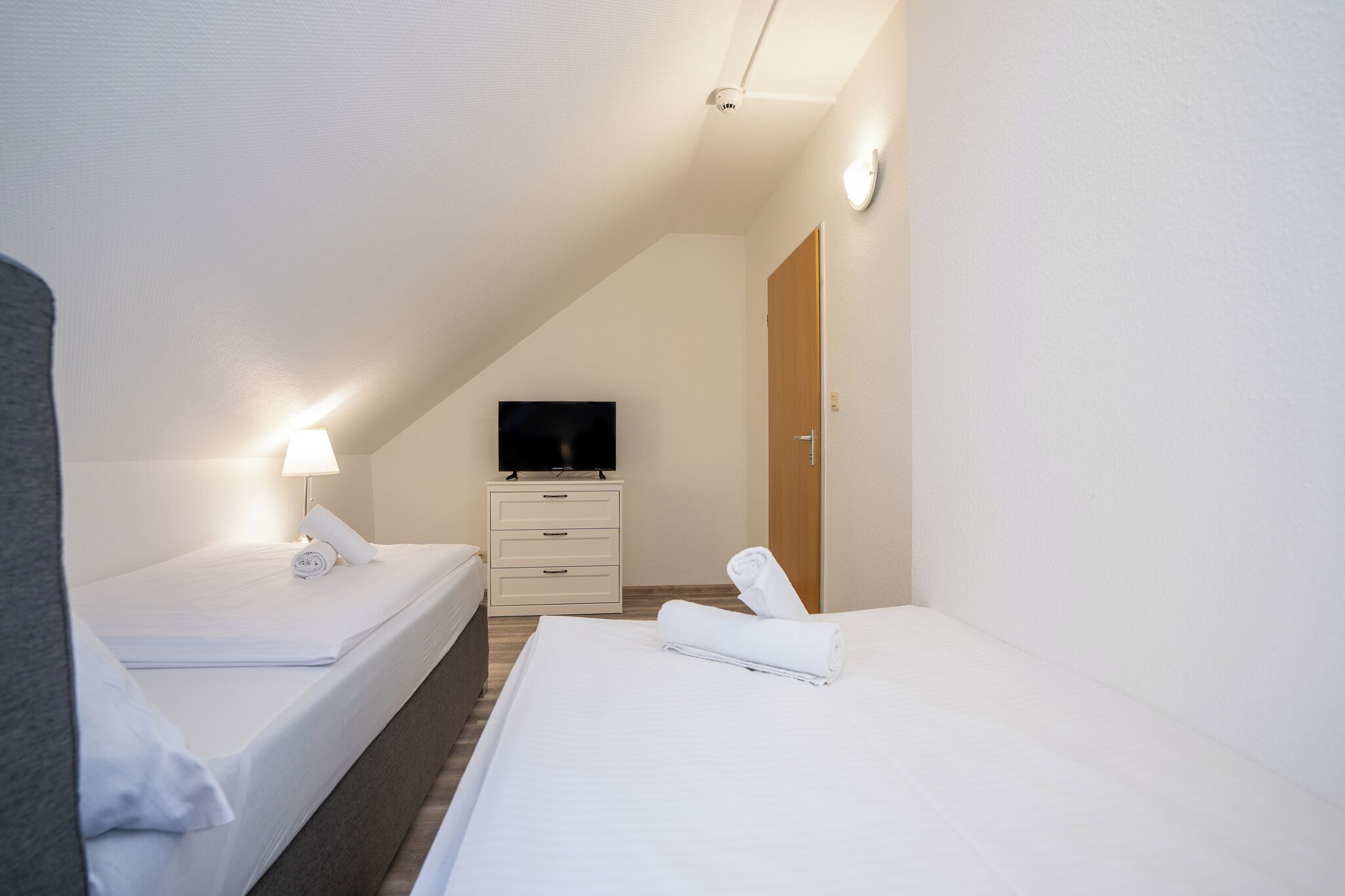 Ein Hotelzimmer mit zwei Betten, einem Fernseher, einem Nachttisch und einer Lampe.