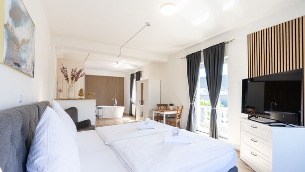 A modern hotel room with a large bed, a desk, a TV, and a bathroom visible in the background. - Hotel Bergheim an der Erft (Bergheim)
