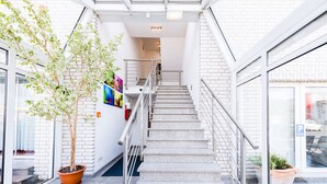 A modern building entrance with a staircase, potted plants, and a glass door. - Hotel Bergheim an der Erft (Bergheim)