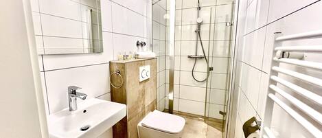 Un baño moderno con lavabo, inodoro y cabina de ducha de vidrio.
