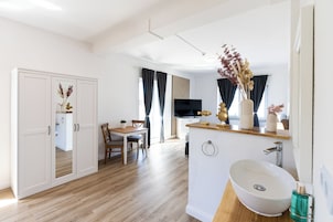 Un baño moderno con un lavabo blanco, un espejo y un mueble de tocador de madera.
