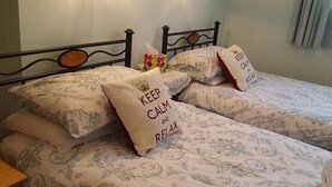 Ein Bett mit blumigem Bettzeug und Kissen mit dem Aufdruck 'KEEP CALM AND RELAX'.