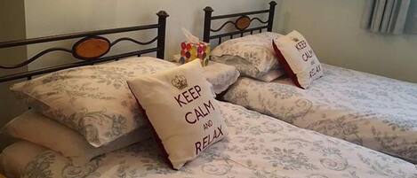 A bed with floral bedding and pillows with "KEEP CALM AND RELAX" text.